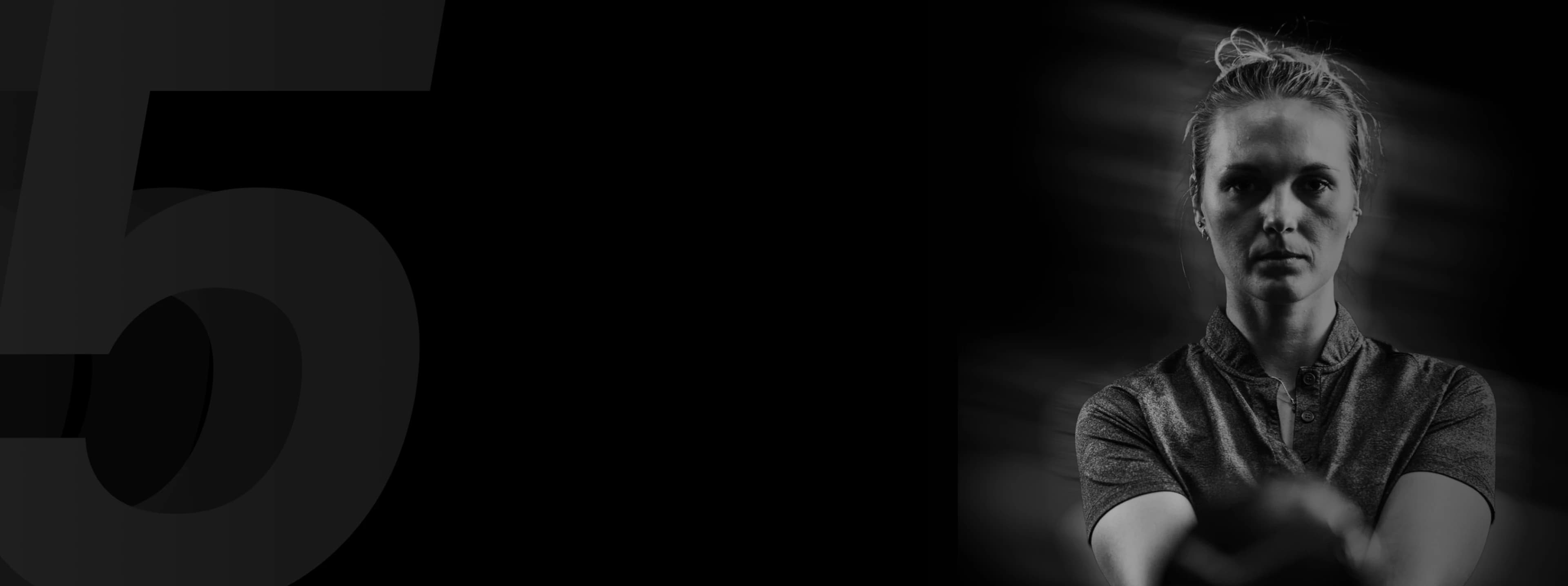 Black and white image of a serious person with a bun, wearing a collared shirt, with a blurred background and a large number 5 on the left.
