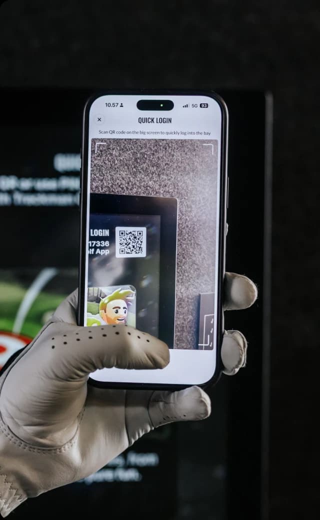A gloved hand holds a smartphone scanning a QR code on a screen for quick login, displaying a virtual character.