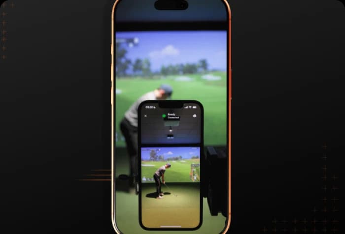 A smartphone showing a golf simulation, with a golfer on the screen preparing to swing, mirrored against a blurred real-life backdrop.