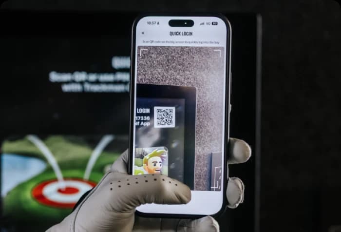 A gloved hand holds a smartphone scanning a QR code on a screen for quick login, displaying a virtual character.
